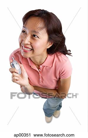 Woman holding mobile phone up, looking away View Large Photo Image Stock Image - Woman holding mobile phone up, looking away. Fotosearch