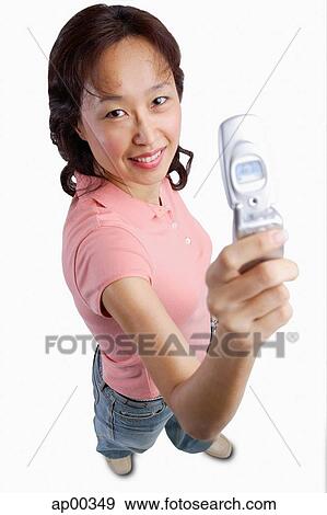 Stock Photo - Woman holding mobile phone up, looking at camera. Fotosearch