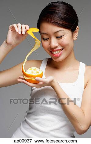 Woman holding orange and pulling orange peel View Large Photo Image Stock Photo - Woman holding orange and pulling orange peel. Fotosearch