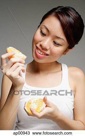 Stock Image - Woman holding peeled orange. Fotosearch
