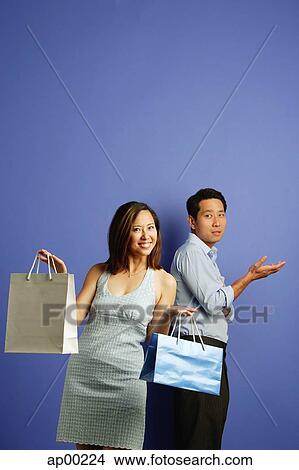 Woman holding shopping bags, man behind her with hand raised View Large Photo Image Picture - Woman holding shopping bags, man behind her with hand raised. Fotosearch