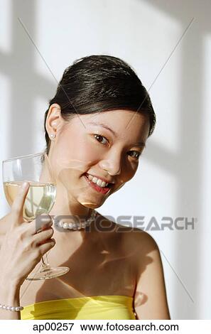 Stock Photo - Woman holding wine glass, smiling at camera. Fotosearch