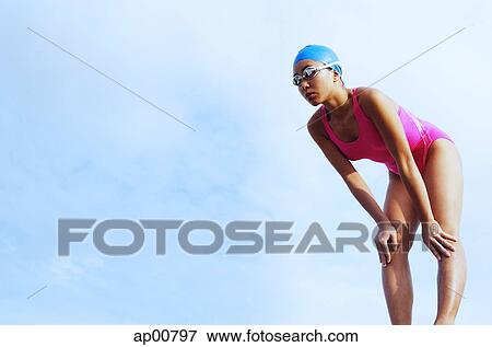 Stock Photo - Woman in swimming costume, bending, hands on knees. Fotosearch