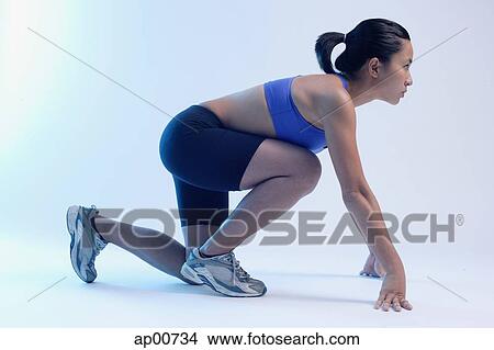 Woman kneeling at starting position, looking up, side view View Large Photo Image Picture - Woman kneeling at starting position, looking up, side view. Fotosearch