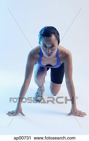 Stock Image - Woman kneeling at starting position, looking at camera. Fotosearch