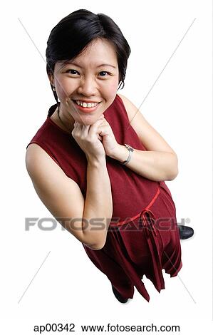 Stock Image - Woman looking at camera, hands clasped under chin. Fotosearch