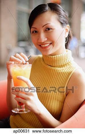Woman looking at camera, holding drink, smiling View Large Photo Image Stock Image - Woman looking at camera, holding drink, smiling. Fotosearch