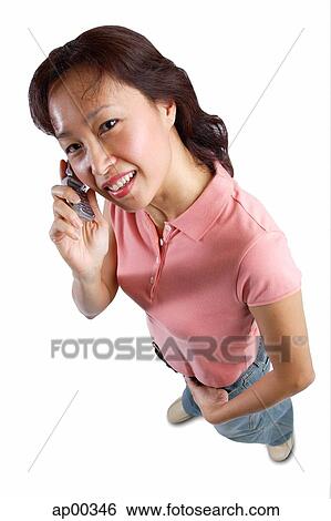 Stock Photograph - Woman looking at camera, using mobile phone. Fotosearch