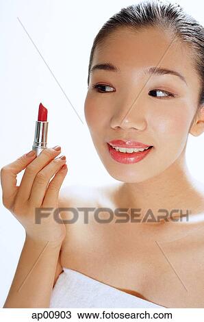 Stock Image - Woman looking at lipstick in her hand. Fotosearch