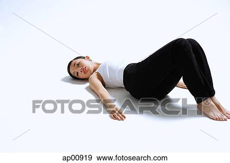 Stock Photo - Woman lying on back, knees up, arms outstretched. Fotosearch