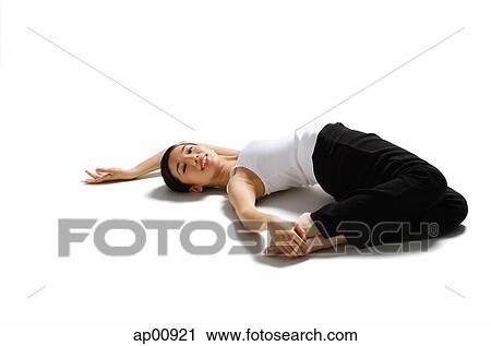 Stock Image - Woman lying on back, pulling feet towards her, looking at camera. Fotosearch