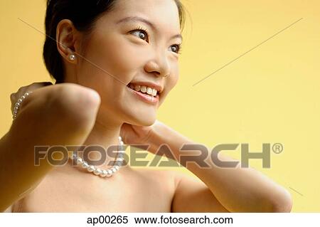 Stock Photography - Woman putting on pearl necklace. Fotosearch