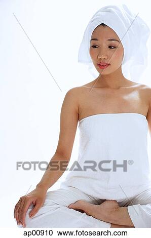 Stock Image - Woman sitting cross legged, wearing towel on head. Fotosearch