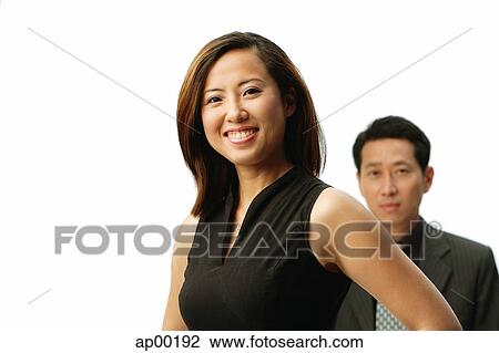 Stock Image - Woman smiling at camera, man behind her. Fotosearch