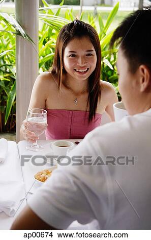 Woman smiling at man sitting across table from her View Large Photo Image Picture - Woman smiling at man sitting across table from her. Fotosearch
