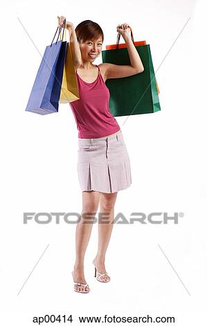 Picture - Woman standing, carrying shopping bags, looking at camera. Fotosearch