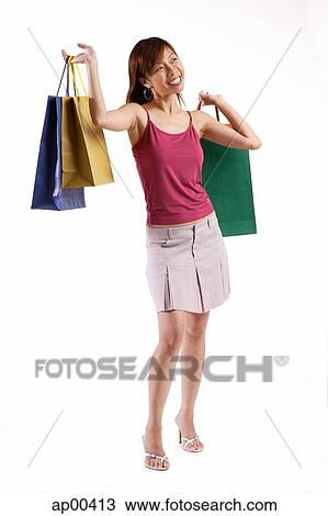 Woman standing, carrying shopping bags in both hands, looking away View Large Photo Image Stock Image - Woman standing, carrying shopping bags in both hands, looking away. Fotosearch