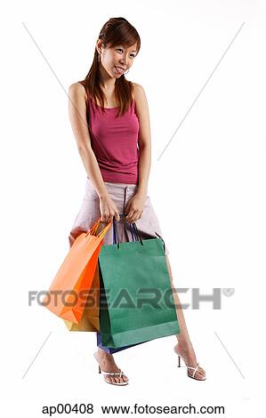 Stock Photo - Woman standing, carrying shopping bags. Fotosearch