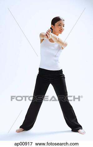 Stock Photo - Woman standing, hands clasped in front of her, legs apart. Fotosearch