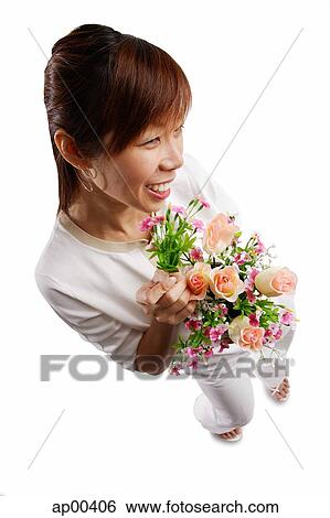 Woman standing, holding bouquet of flowers, looking away View Large Photo Image Stock Photograph - Woman standing, holding bouquet of flowers, looking away. Fotosearch