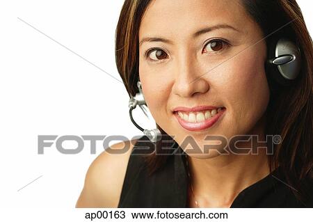 Stock Image - Woman using headset, portrait. Fotosearch