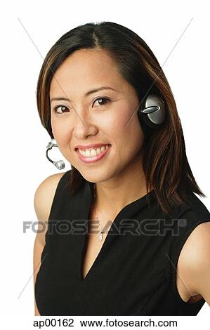 Stock Image - Woman using headset, smiling at camera. Fotosearch
