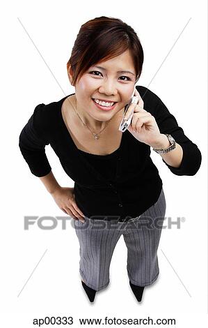 Stock Image - Woman using mobile phone, looking up at camera. Fotosearch