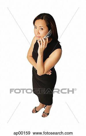 Stock Photo - Woman using mobile phone, looking up at camera. Fotosearch