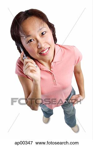 Stock Photo - Woman using mobile phone, looking up at camera. Fotosearch
