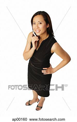 Stock Image - Woman using mobile phone, smiling up at camera. Fotosearch