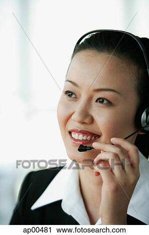 Stock Image - Woman wearing headset, smiling, portrait. Fotosearch