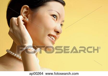 Woman wearing pearl necklace and bracelet, looking away View Large Photo Image Picture - Woman wearing pearl necklace and bracelet, looking away. Fotosearch