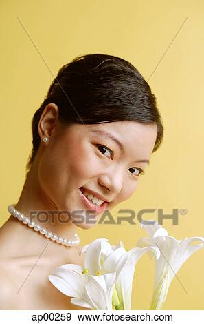 Woman wearing pearl necklace, holding flowers View Large Photo Image Stock Photo - Woman wearing pearl necklace, holding flowers. Fotosearch