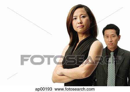 Woman with arms crossed, looking at camera, man behind her View Large Photo Image Stock Image - Woman with arms crossed, looking at camera, man behind her. Fotosearch