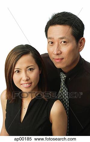 Stock Photography - Woman with arms crossed, looking at camera, man behind her. Fotosearch