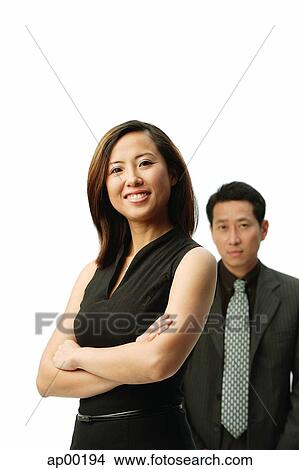 Picture - Woman with arms crossed, smiling at camera, man standing behind her. Fotosearch