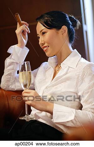 Woman with champagne glass and cigar, looking away View Large Photo Image Picture - Woman with champagne glass and cigar, looking away. Fotosearch