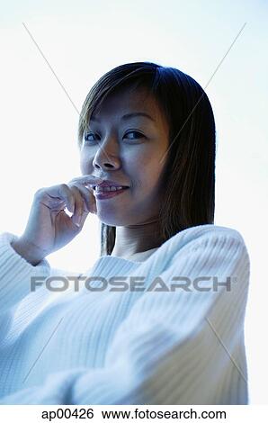 Stock Photograph - Woman with hand on mouth, looking at camera. Fotosearch