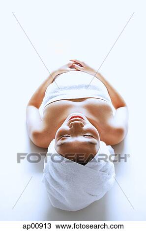 Stock Image - Woman wrapped in a towel, lying down, eyes closed. Fotosearch