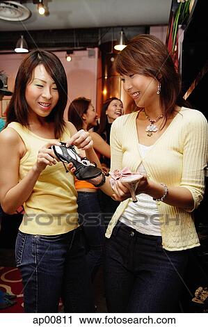 Stock Image - Women looking at shoes in shop. Fotosearch