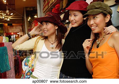 Women shopping, trying on hats, looking away View Large Photo Image Stock Photo - Women shopping, trying on hats, looking away. Fotosearch