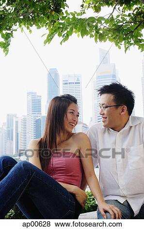 Stock Photo - Young couple sitting and looking at each other. Fotosearch