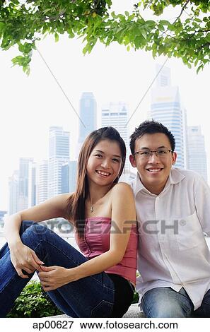 Young couple sitting on park bench, looking at camera View Large Photo Image Stock Photo - Young couple sitting on park bench, looking at camera. Fotosearch