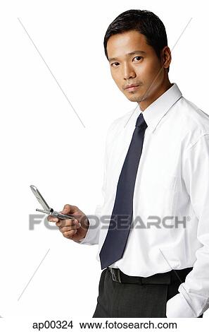 Picture - Young executive, holding mobile phone, looking at camera. Fotosearch