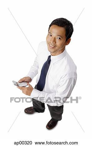 Young executive, holding mobile phone, looking at camera View Large Photo Image Stock Image - Young executive, holding mobile phone, looking at camera. Fotosearch