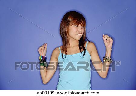 Stock Photo - Young woman against blue background, looking away. Fotosearch