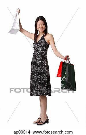Young woman carrying shopping bags, arms outstretched View Large Photo Image Picture - Young woman carrying shopping bags, arms outstretched. Fotosearch