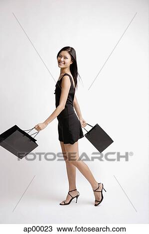 Young woman, carrying shopping bags, looking at camera View Large Photo Image Stock Image - Young woman, carrying shopping bags, looking at camera. Fotosearch