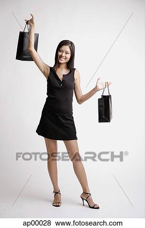Young woman carrying shopping bags, smiling View Large Photo Image Stock Photo - Young woman carrying shopping bags, smiling. Fotosearch