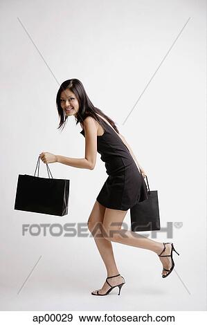 Stock Photo - Young woman carrying shopping bags. Fotosearch